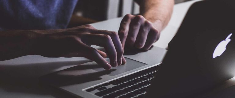 Ein Mann tippt mit seinen Händen auf einer Laptop-Tastatur
