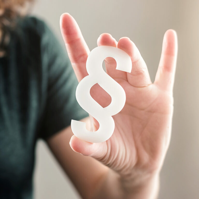 Eine Frau hält ein Paragraph-Symbol in ihrer Hand